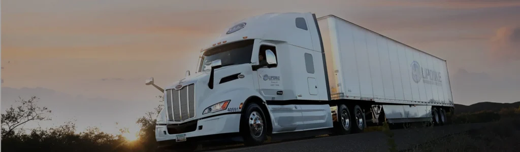 Updike Distribution Logistics semi truck driving at dusk